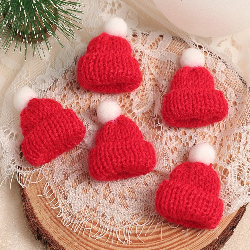 A set of mini knitted red and white hats and scarves for doll dress-up accessories displayed on a lace fabric.