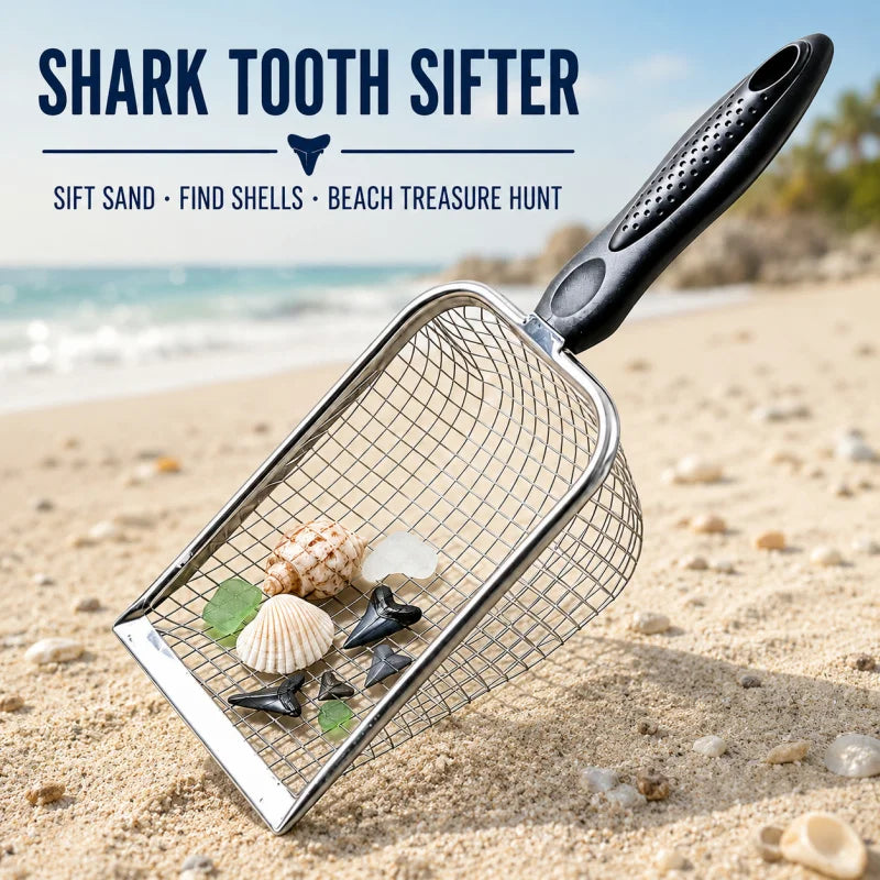 A silver shark tooth sifter tool is shown scooping seashells and small treasures from light-colored beach sand.