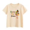A light beige short-sleeve t-shirt featuring a colorful illustration of a black bird with a top hat and green and yellow acce