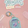 A light blue fabric bag with a purple and white design featuring a monster theme, used as a pendant keychain.