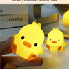 A hand holds a glowing yellow cartoon duck night light, illuminating a dark surface.