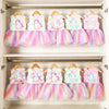 A row of five unicorn themed skirt outfits for 18-inch dolls displayed on a wooden rack.