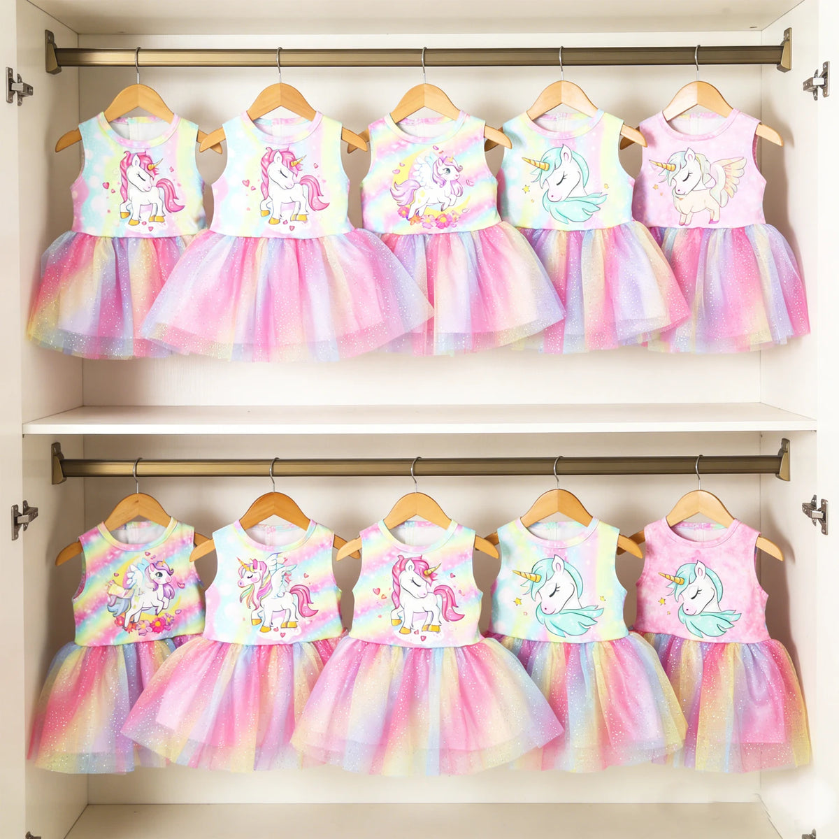 A row of five unicorn themed skirt outfits for 18-inch dolls displayed on a wooden rack.