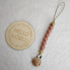 A wooden bead pacifier clip with silicone teether strung on a leather cord against a white background.