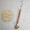 A string of light pink wooden beads attached to a clip for a pacifier or teether.