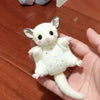 A small white plush flying mouse charm with large ears and a cute expression is held in a hand.