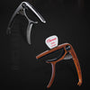 A professional metal guitar capo with a pick holder shown in a close-up view.