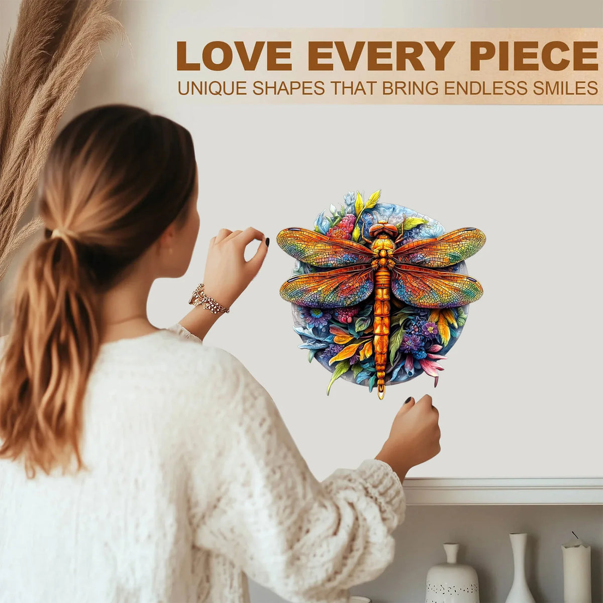 A woman holds up a colorful wooden jigsaw puzzle shaped like a butterfly against a light background.