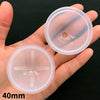 A hand holds two clear silicone molds for resin crafting, one with a circular opening and the other with a cross shape.