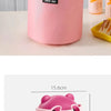 Pink stackable bento lunch bag with a bear face design and pink glass jar visible on a table.