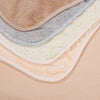 A stack of soft cotton baby bibs in various neutral colors including beige, gray, and cream.