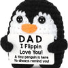 A black and white penguin plush toy with a sign that reads Dad I Flippin Love You
