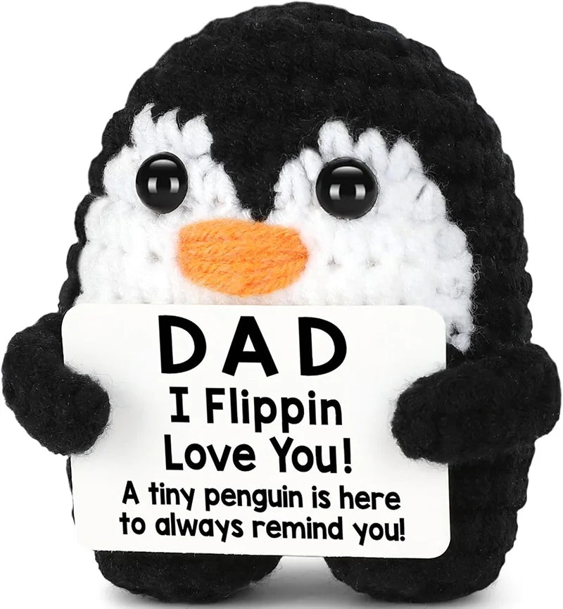 A black and white penguin plush toy with a sign that reads Dad I Flippin Love You