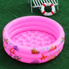 A pink inflatable kids play pool with a cartoon sea creature design resting on green grass.