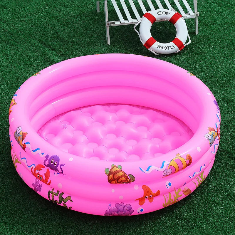 A pink inflatable kids play pool with a cartoon sea creature design resting on green grass.