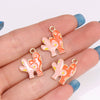 A hand holds several orange and pink enamel marine life charms for jewelry making