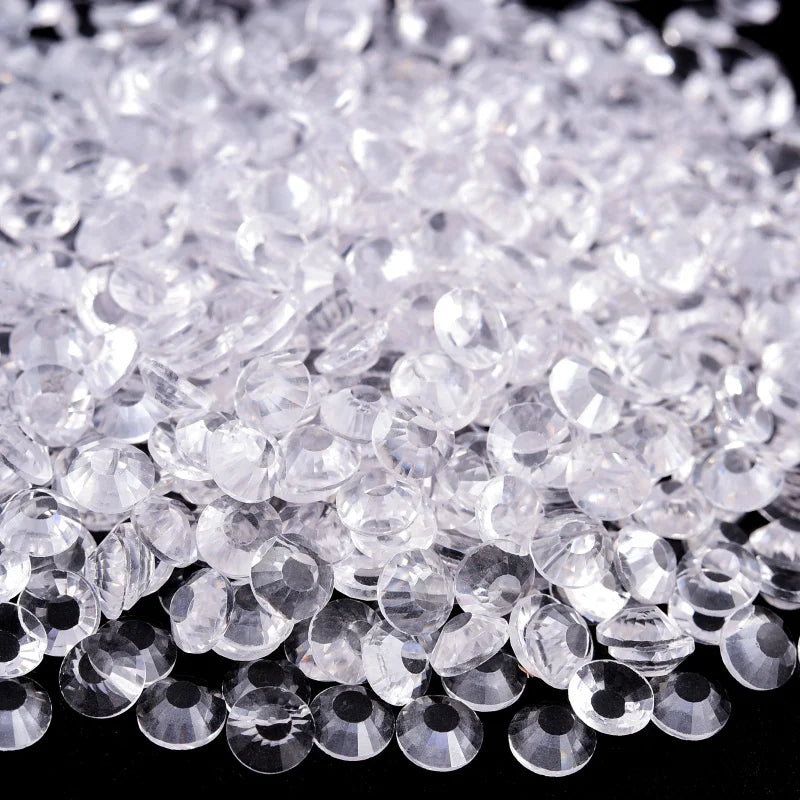 A pile of clear, sparkling crystal flatback rhinestones for nail art and crafts.