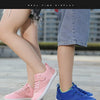 A pair of pink and blue kids barefoot training sneakers are shown on a person's feet.