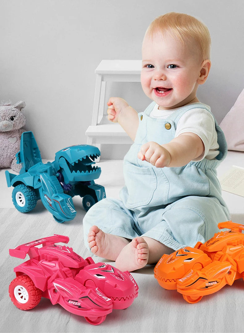 A smiling baby is sitting on the floor surrounded by various pink and blue dinosaur transforming car toys.