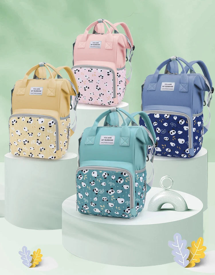 A collection of pink, yellow, and blue mommy backpacks with wet/dry separation features displayed on tiered white pedestals.