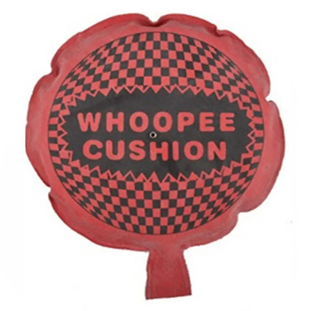 A red, circular toy with a black and pink checkered pattern and the text WHOOPEE CUSHION.