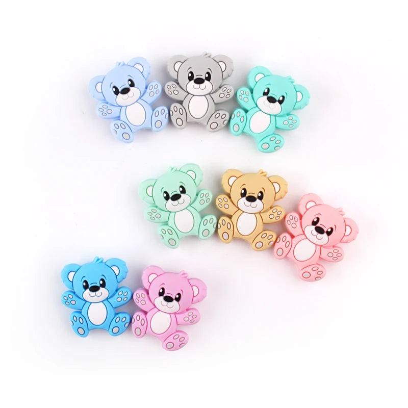 A collection of colorful cartoon silicone bear beads in blue, gray, mint green, and pink for jewelry making