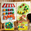 A child interacts with a felt board featuring fruit and vegetable shapes and daily life scenarios.