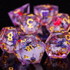 A close-up of a set of iridescent plum blossom liquid core resin dice reflecting on a dark surface.