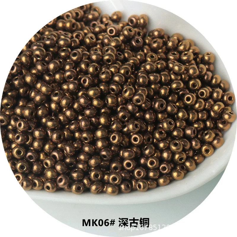 A pile of small, round, gold-colored metallic glass beads for jewelry and crafting.