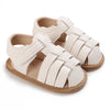 A pair of light beige breathable baby first walker sandals with a woven strap design and soft anti-slip sole.