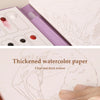 A close-up of thickened watercolor paper and a brush on a coloring book page showing line art.