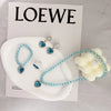 A set of five sparkling blue and clear gemstone necklaces and earrings displayed on a white surface.