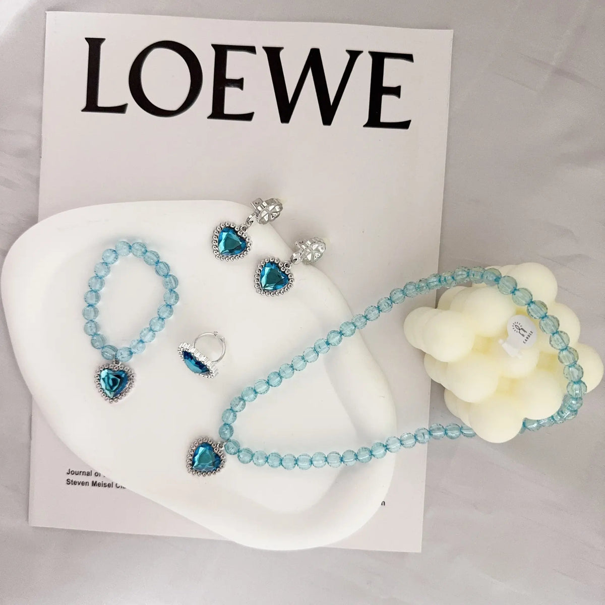 A set of five sparkling blue and clear gemstone necklaces and earrings displayed on a white surface.