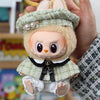 A handmade doll wearing a green plaid cape and beret set with light brown fur accents