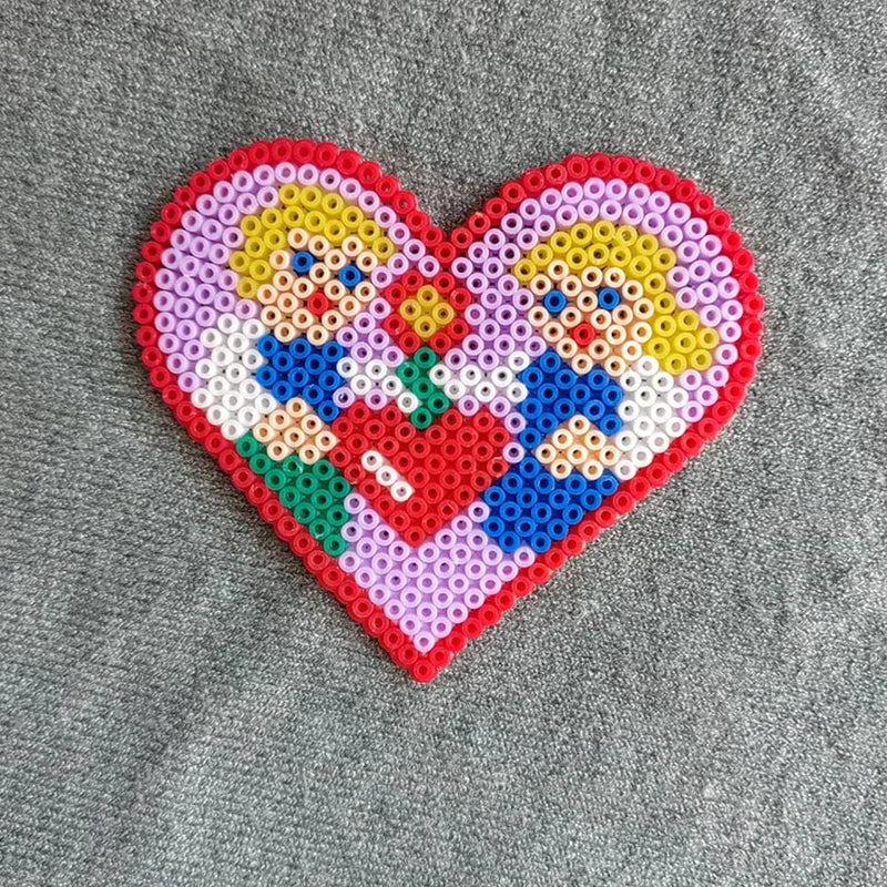 A heart-shaped mosaic created from colorful fuse beads depicting two stylized female figures.