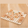 A wooden strategy chess game board with pieces set up on a light wood surface.
