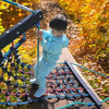 A young boy is playing on a playground structure made of black and blue hooks and loops outdoors.