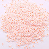 A pile of small, round polymer clay flower charms in shades of pink and orange.