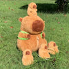 A brown capybara plush family set featuring a mother and four baby capybaras lying in green grass.