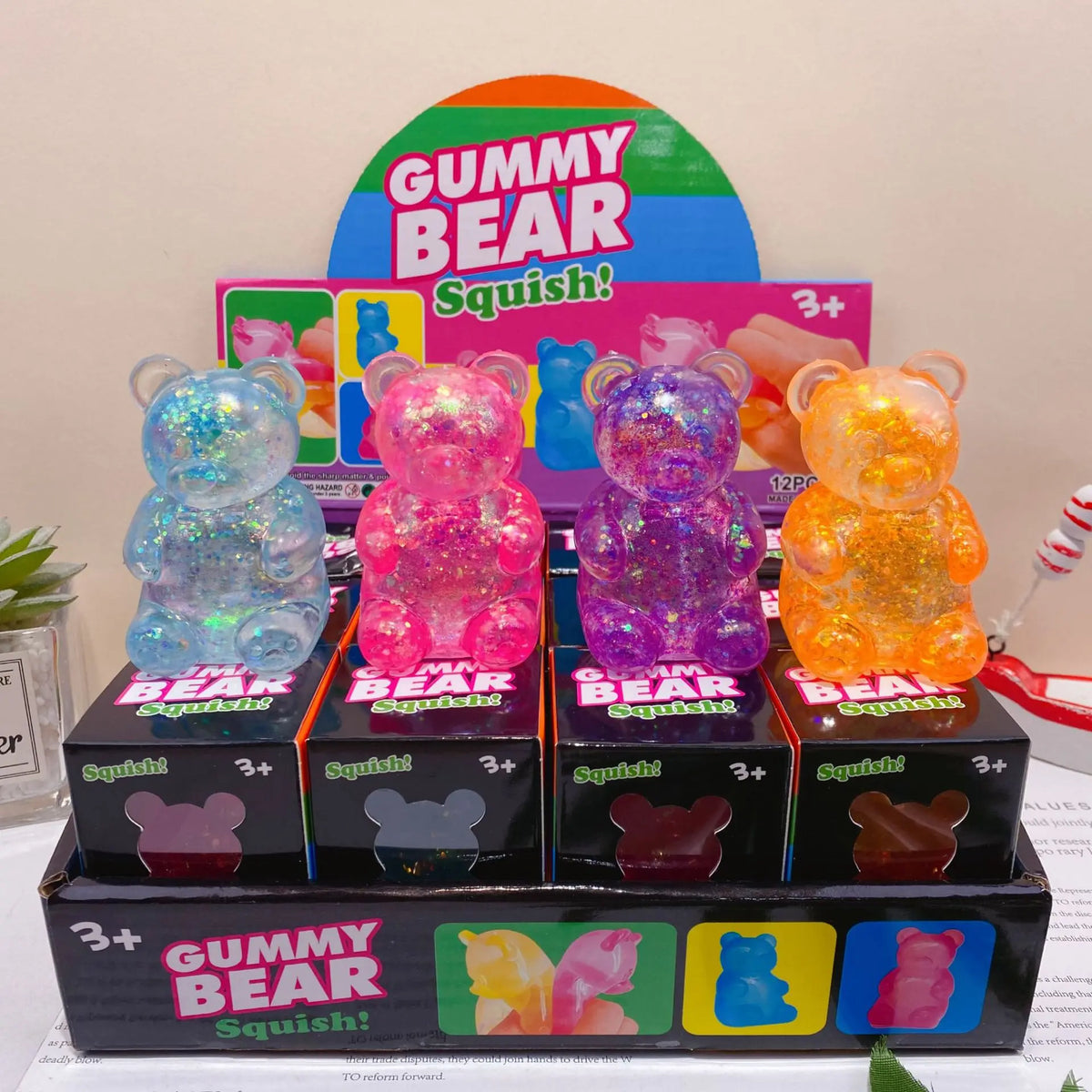 A box of Gummy Bear Squish glitter bear toys with a large graphic featuring the title and various colored bears.