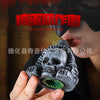 A hand holds a gray Aztec death whistle skull, an eerie screaming noise maker, against a dark background.