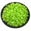 A pile of bright lime green acrylic round beads for jewelry making.