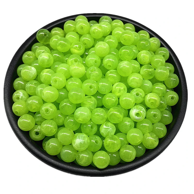 A pile of bright lime green acrylic round beads for jewelry making.