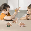 Two children are playing with wooden dinosaur teether toys on a table.