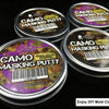 Several tins of Camo Masking Putty for model painting are displayed on a dark surface.