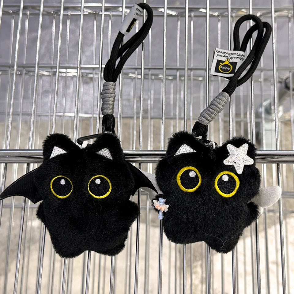 A black plush cat keychain charm with yellow eyes and a white star detail hanging from a black cord.