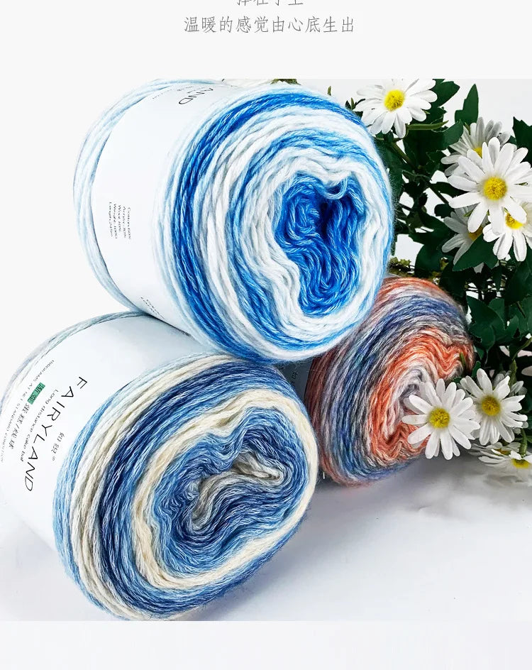 Spools of gradient rainbow cotton-wool yarn showing various shades of blue, white, orange, and green.