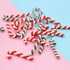 A pile of red and white striped polymer clay marshmallow charms scattered on a pink background.