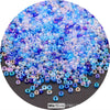 A close-up view of a mix of colorful round glass seed beads in various shades of blue and purple.