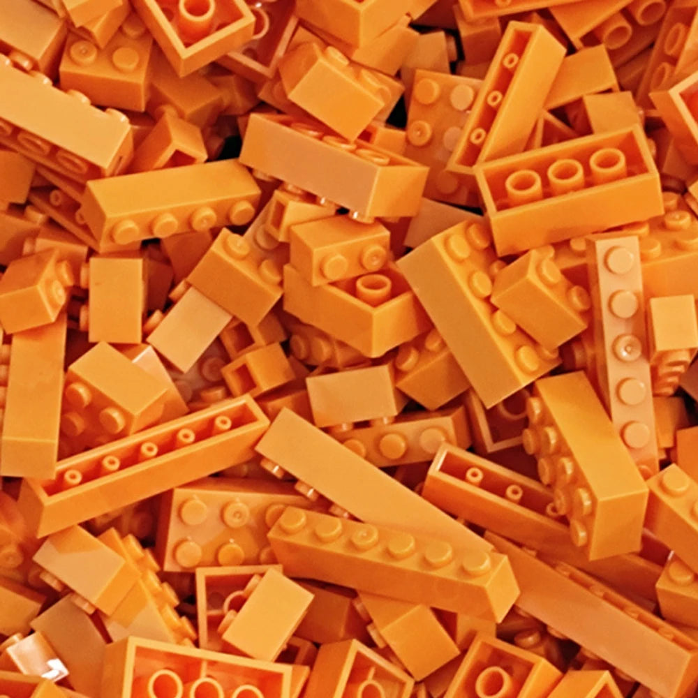 A close-up view of a bulk set of colorful, square building blocks in various shades of orange and yellow.